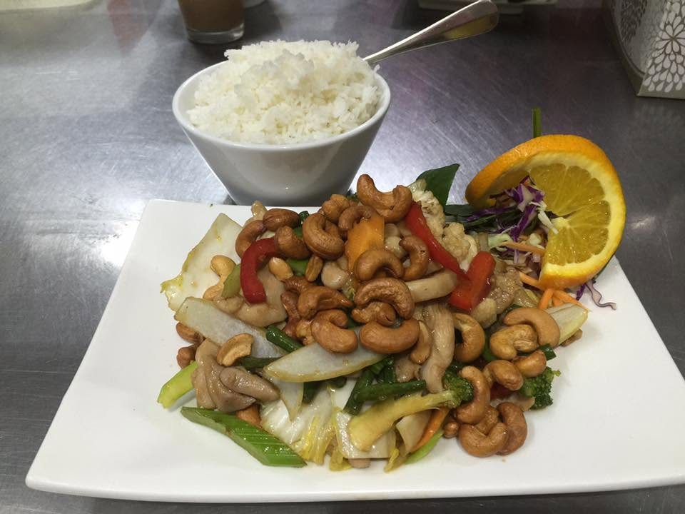 A cashew nut stir-fry with vegetables, orange and a bowl of rice