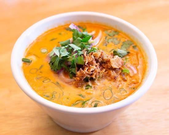 A bowl of laksa topped with herbs and fried shallots