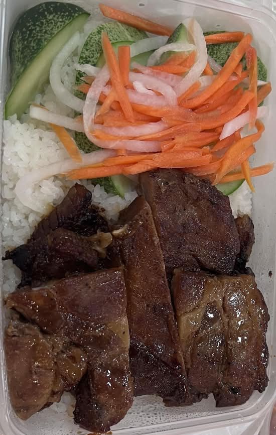 Grilled pork chop on rice with pickled carrot, cucumber and lettuce